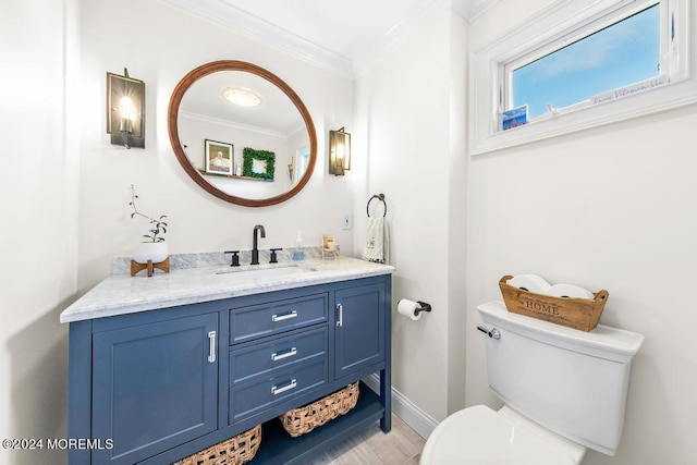 bathroom featuring toilet, ornamental molding, wood finished floors, baseboards, and vanity