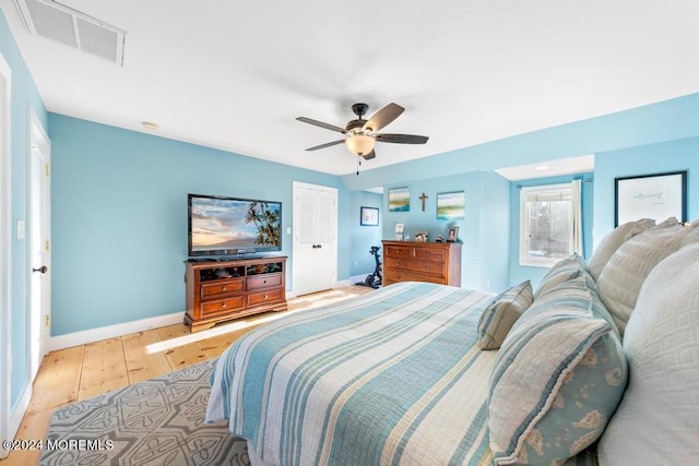 bedroom with visible vents, light wood-style flooring, a ceiling fan, a closet, and baseboards