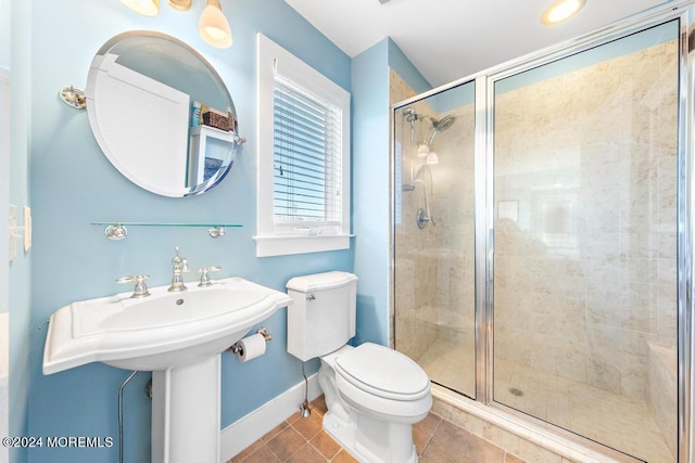 bathroom with tile patterned flooring, a shower stall, toilet, and baseboards