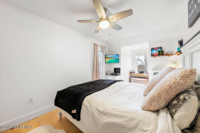 bedroom featuring a ceiling fan, baseboards, and wood finished floors