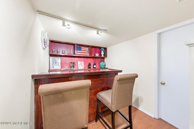 bar with track lighting, a dry bar, baseboards, and light wood-type flooring