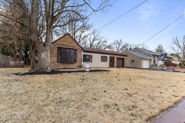 ranch-style home featuring a front yard, fence, and a garage