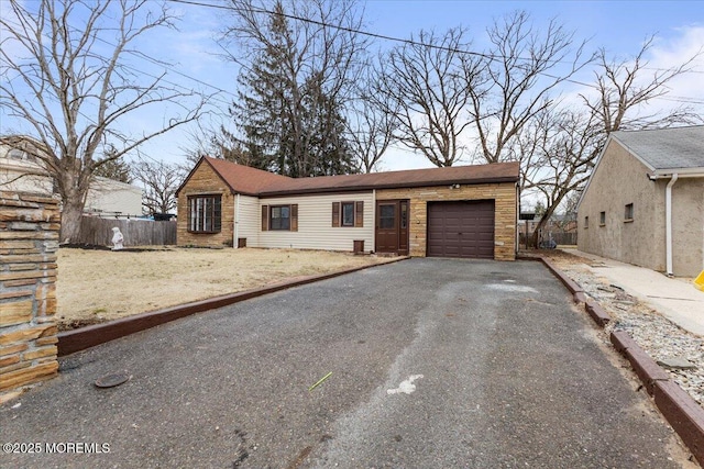 view of front of property with aphalt driveway, an attached garage, and fence