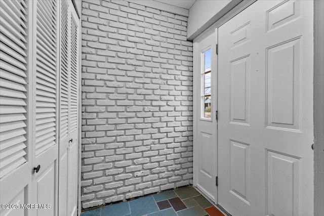 entrance foyer featuring brick wall