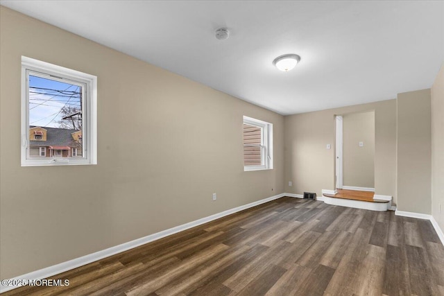 empty room with visible vents, baseboards, and dark wood-type flooring