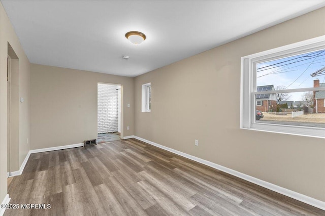 unfurnished room featuring visible vents, baseboards, and wood finished floors