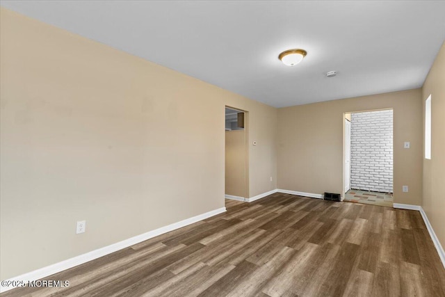 spare room featuring visible vents, baseboards, and wood finished floors