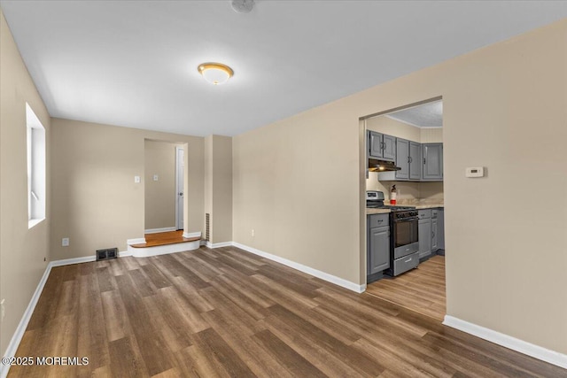 unfurnished living room with visible vents, baseboards, and dark wood-style floors