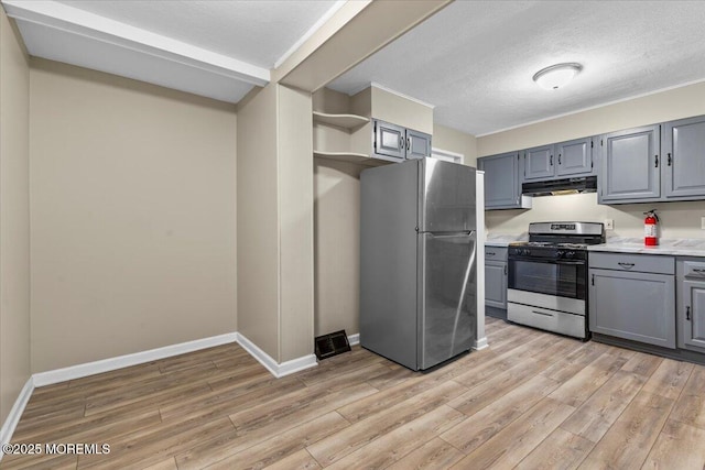 kitchen with light wood-type flooring, gray cabinetry, under cabinet range hood, appliances with stainless steel finishes, and light countertops