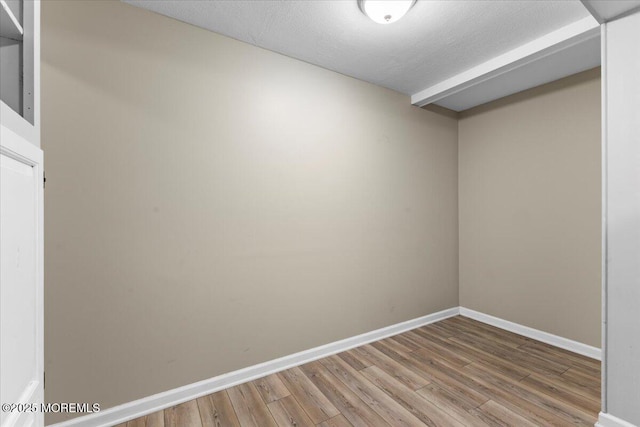 unfurnished room with a textured ceiling, light wood-type flooring, and baseboards