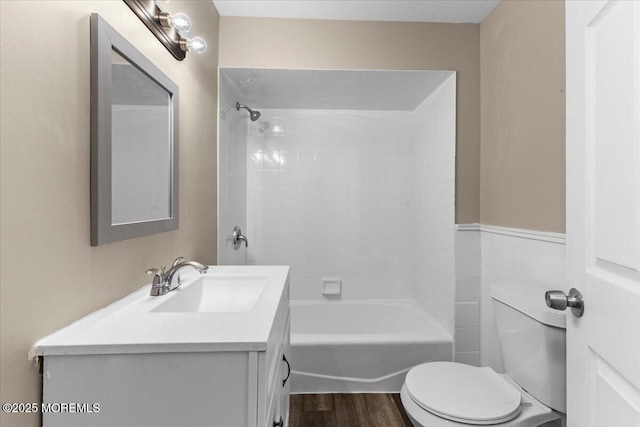 bathroom featuring toilet, vanity,  shower combination, and wood finished floors