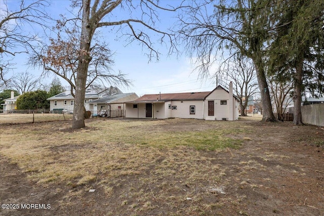 back of property featuring fence and a lawn