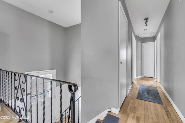 hallway with an upstairs landing, baseboards, and wood-type flooring