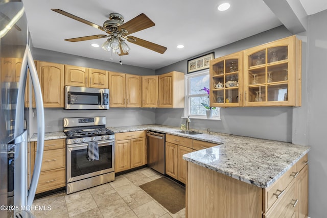 kitchen with glass insert cabinets, light stone counters, recessed lighting, appliances with stainless steel finishes, and a sink