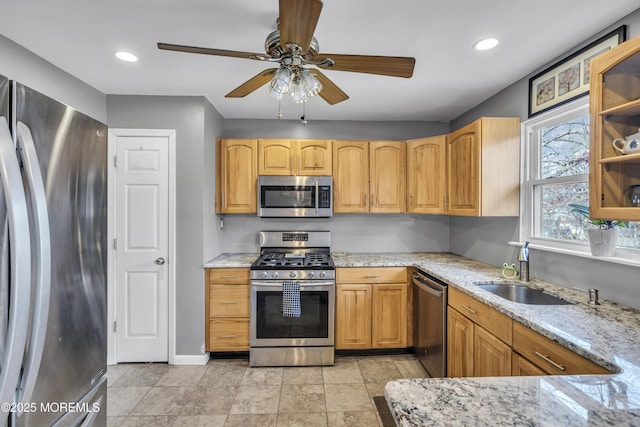 kitchen with light stone countertops, recessed lighting, stainless steel appliances, a ceiling fan, and a sink