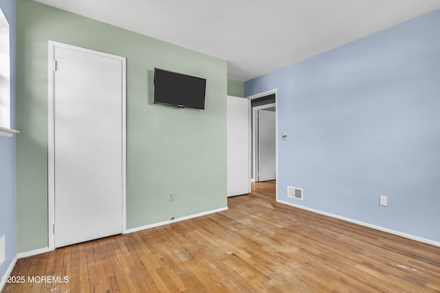 unfurnished bedroom with hardwood / wood-style flooring, baseboards, and visible vents