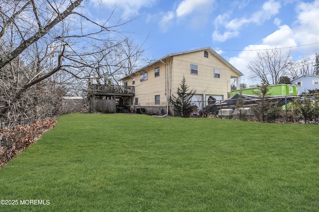 rear view of house featuring a wooden deck, a yard, and fence