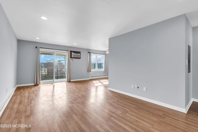 unfurnished room featuring a baseboard heating unit, baseboards, wood finished floors, and a wall unit AC