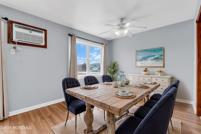 dining space with an AC wall unit, baseboards, and light wood finished floors