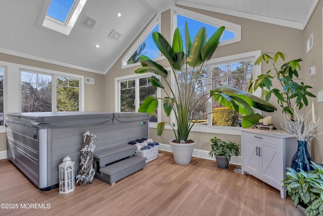 misc room featuring light wood finished floors, visible vents, vaulted ceiling with skylight, and ornamental molding