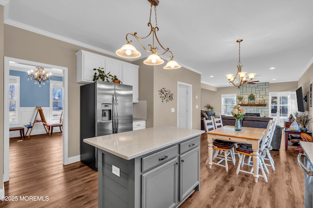 kitchen featuring gray cabinetry, ornamental molding, open floor plan, an inviting chandelier, and stainless steel fridge with ice dispenser