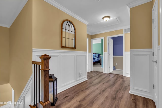 hallway featuring visible vents, crown molding, dark wood finished floors, attic access, and wainscoting