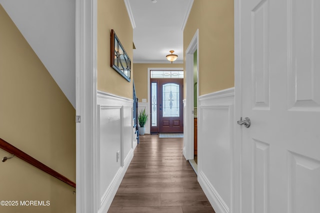 entryway with a decorative wall, a wainscoted wall, crown molding, and wood finished floors