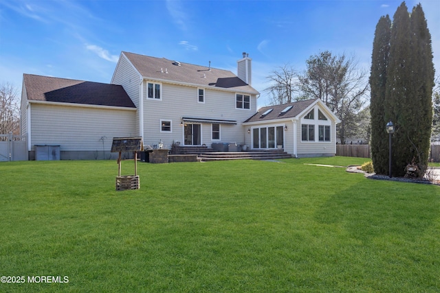 rear view of house featuring entry steps, a lawn, a chimney, and fence