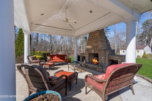 view of patio with a gazebo, a ceiling fan, and an outdoor living space with a fireplace