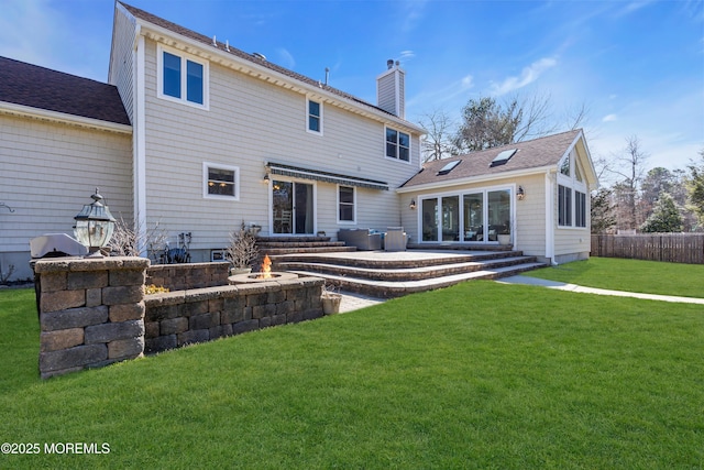 back of house featuring a yard, fence, a chimney, and entry steps