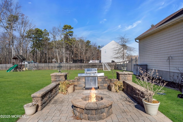 view of patio / terrace with a fire pit, a grill, a fenced backyard, and a playground