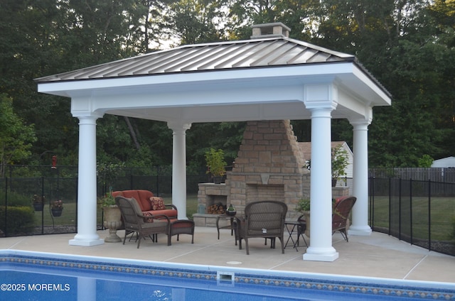 view of pool with a patio, fence, a fenced in pool, an outdoor stone fireplace, and a gazebo