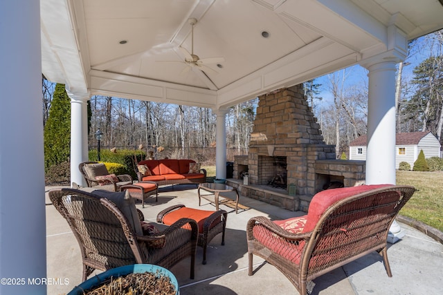 view of patio with a gazebo, an outdoor living space with a fireplace, and ceiling fan