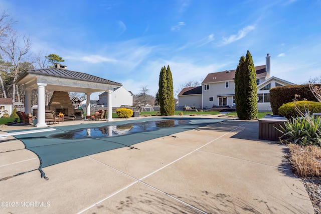 view of swimming pool with a covered pool, fence, a gazebo, an outdoor stone fireplace, and a patio