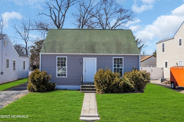 view of front of house with entry steps, a front yard, and fence