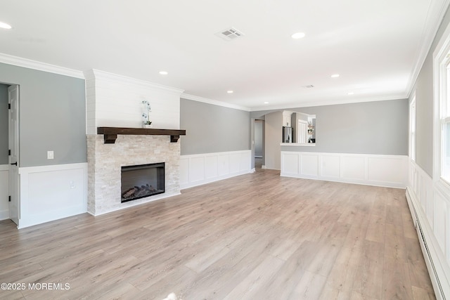 unfurnished living room featuring light wood finished floors, visible vents, ornamental molding, baseboard heating, and a stone fireplace