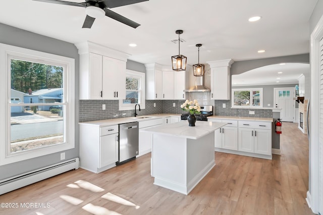 kitchen with a baseboard radiator, a peninsula, arched walkways, a sink, and appliances with stainless steel finishes