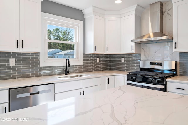 kitchen with a sink, white cabinets, appliances with stainless steel finishes, wall chimney exhaust hood, and backsplash