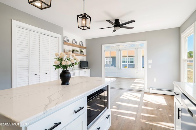 kitchen with a baseboard heating unit, light wood-style flooring, and white cabinetry