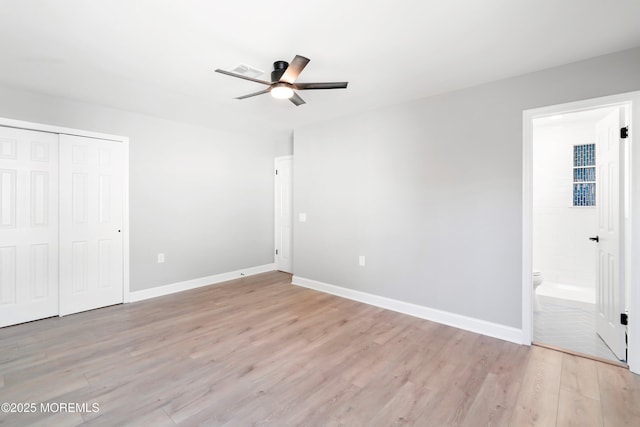 unfurnished bedroom featuring visible vents, baseboards, a closet, ensuite bathroom, and light wood-type flooring