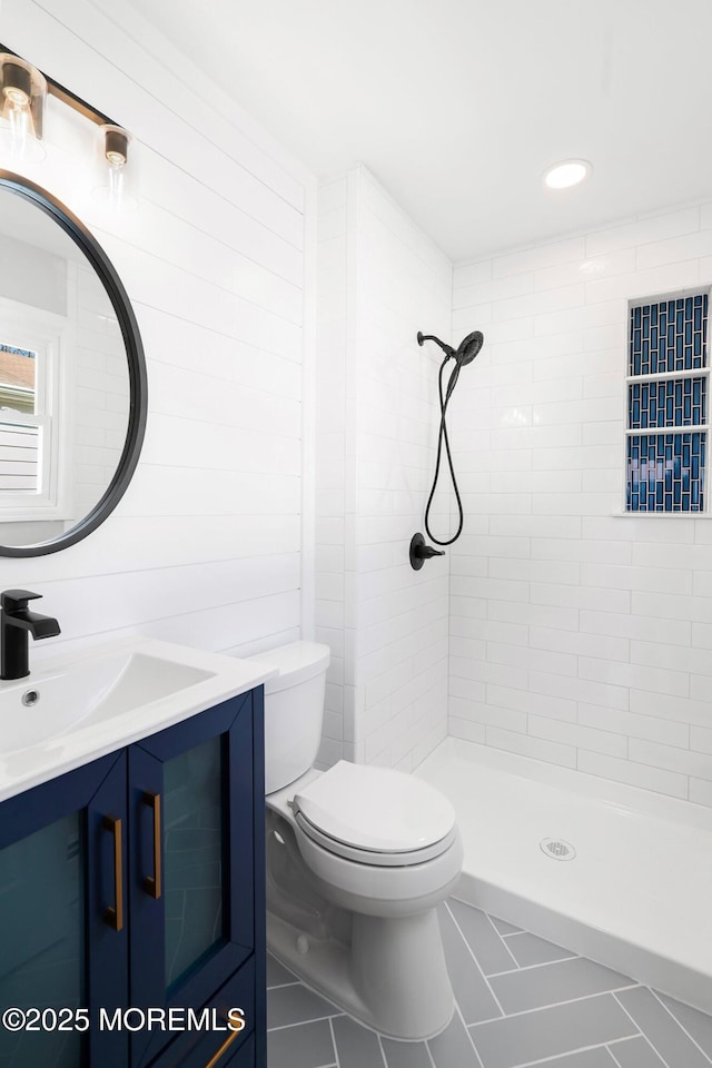 full bathroom with tiled shower, toilet, and vanity