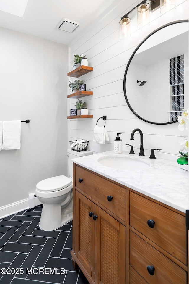 bathroom featuring a baseboard heating unit, toilet, vanity, and baseboards