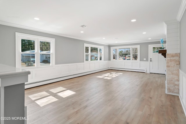 unfurnished living room with wood finished floors, plenty of natural light, ornamental molding, and wainscoting