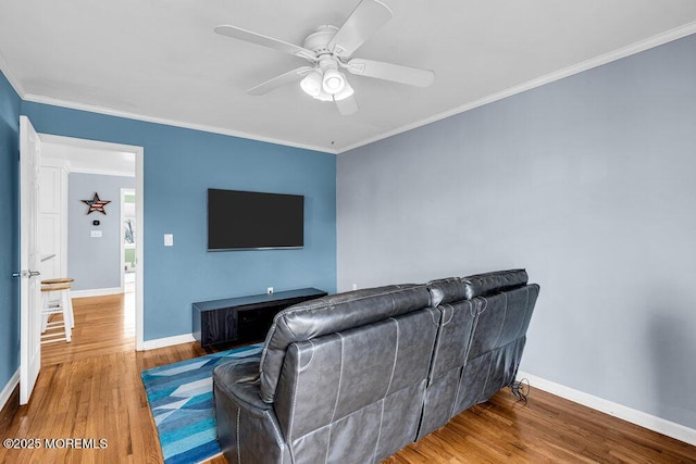 living room with ceiling fan, baseboards, wood finished floors, and crown molding