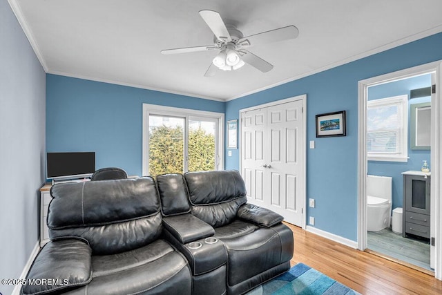 cinema featuring ceiling fan, baseboards, light wood-style floors, and ornamental molding