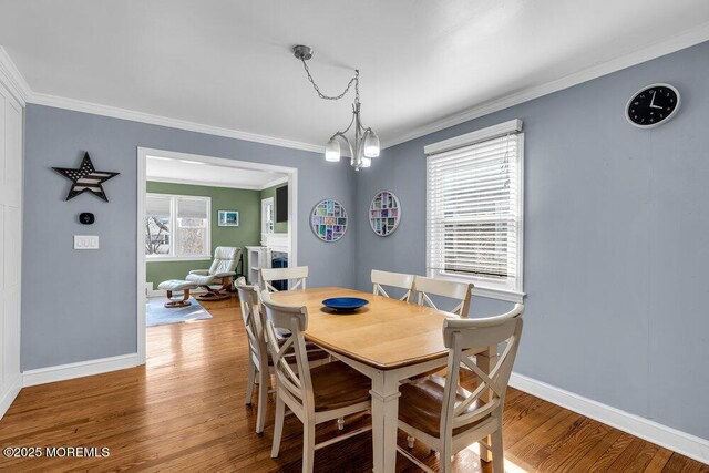 dining area with crown molding, wood finished floors, and a chandelier