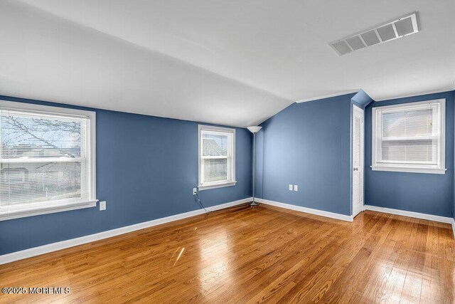 bonus room featuring vaulted ceiling, visible vents, baseboards, and wood-type flooring