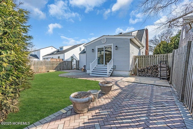 back of property with a fenced backyard, entry steps, a yard, and a patio