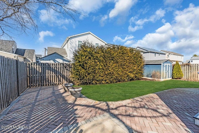 view of yard featuring a patio, an outbuilding, a fenced backyard, and a shed