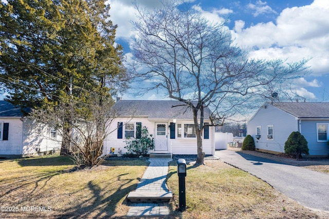 view of front of house with aphalt driveway, a shingled roof, and a front lawn